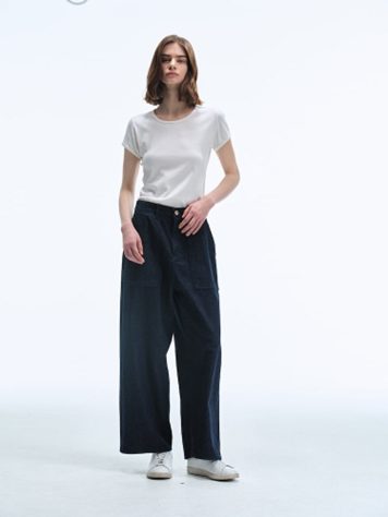 A female model poses in a studio wearing Women Selvedge Loose Straight Fit Denim in Deep Navy with a simple white T-shirt and white sneakers, highlighting the structured yet relaxed fit and rich indigo tone.