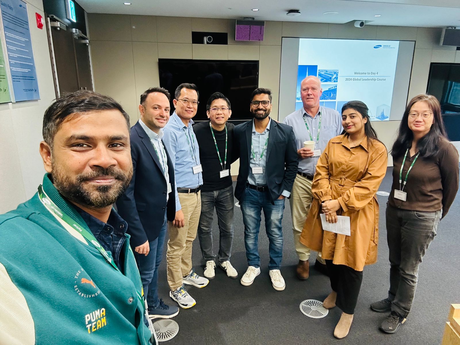 A team of employees at Samsung C&T E&C, including individuals in diverse roles, standing together for a group photo during a global leadership event.