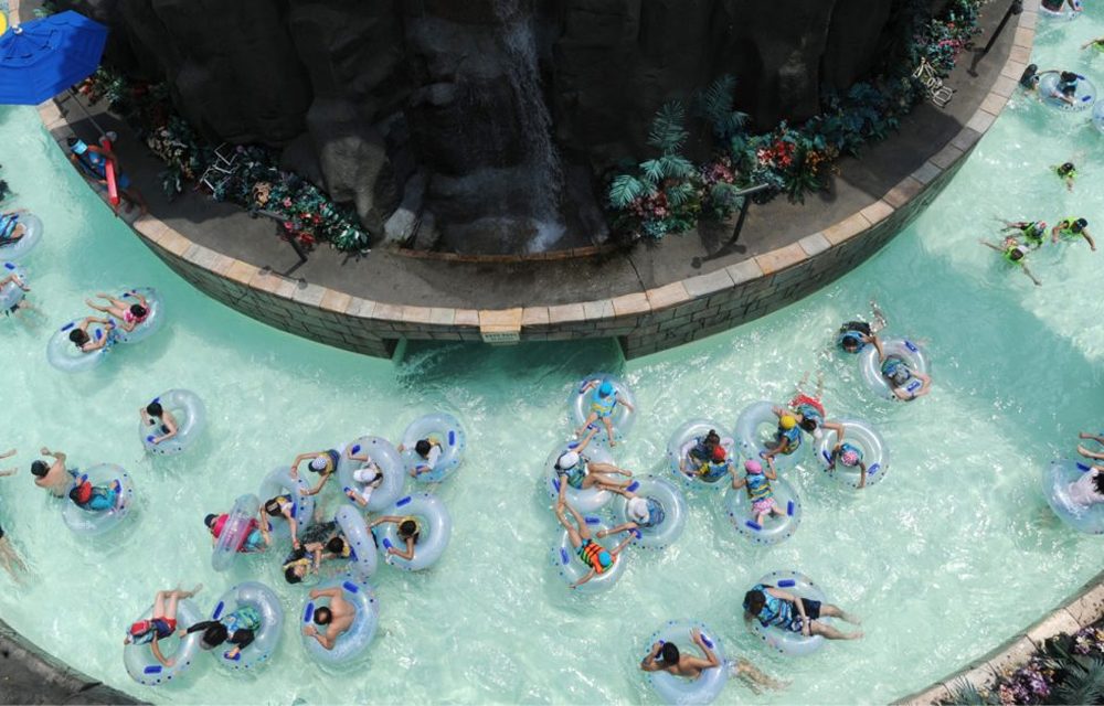 Dozens of guests relax in inner tubes as they float along the winding Lazy River at Caribbean Bay on a sunny day.