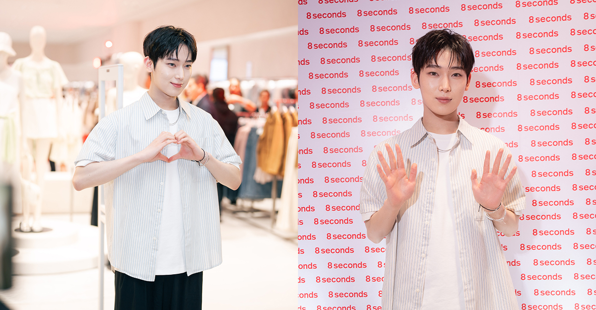 ENHYPEN’s SUNOO poses at the 8 Seconds Manila store, making finger hearts and waving in front of fans and a branded step-and-repeat wall while wearing a striped short-sleeve shirt layered over a white tee