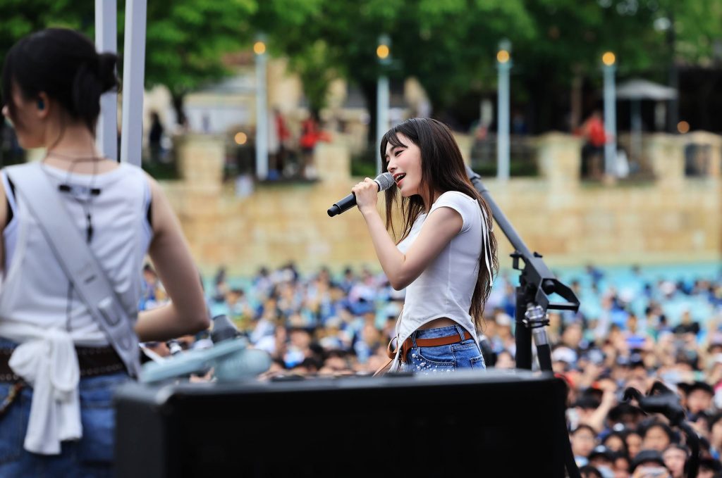 A performer sings on stage during Caribbean Bay’s Water Music Pool Party, as a packed audience watches from the wave pool area.