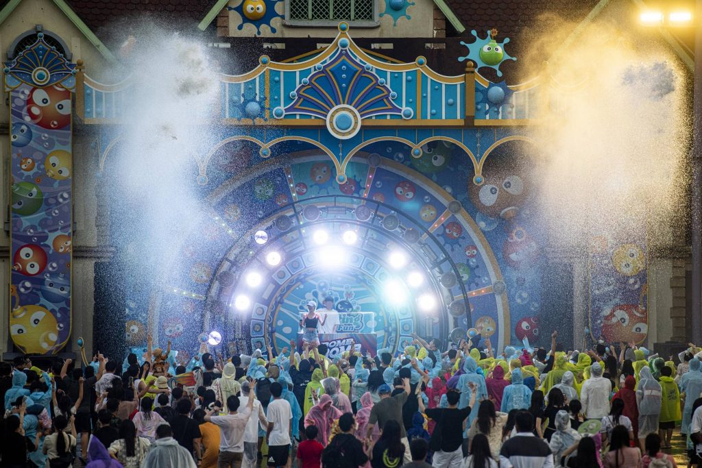 Guests in colorful rain ponchos cheer at Everland’s Bam Bam Summer Night show, as mist sprays across the crowd and lights flash from the stage.