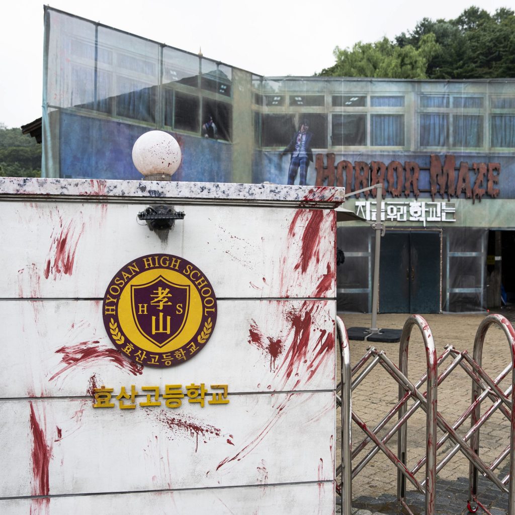 A horror maze entrance designed as Hyosan High School, complete with a blood-smeared school sign and a two-story set, created for Everland’s Blood City 8 festival in collaboration with Netflix.