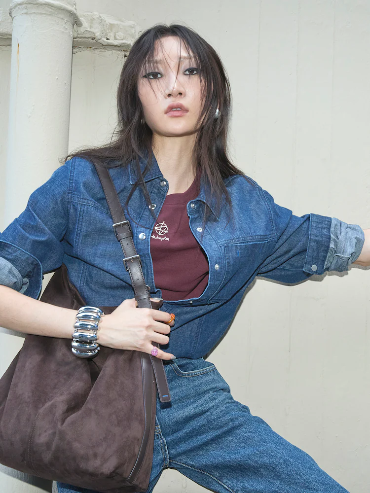 Female model wearing the kuho plus Denim Regular Fit Shirt in Blue, styled with a burgundy top and mid-wash denim trousers. The shirt is crafted from 100% cotton and features subtle pocket detailing, making it versatile for both casual layering and polished outfits.