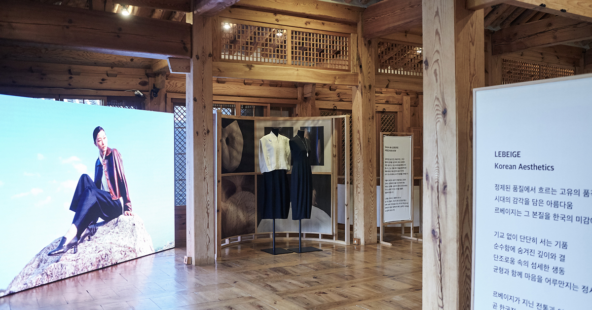 Exhibition view at the Korea Furniture Museum featuring LEBEIGE’s 25FW Signature Coat Collection displayed alongside large-scale visuals and signage highlighting the theme “Korean Aesthetics.”