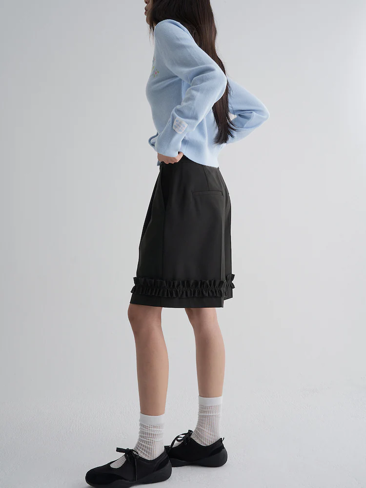 The 8seconds MINJUKIM Frill Bermuda Pants in Black, designed with a knee-length cut and finished with layered ruffle detailing along the hemline. The structured fit and subtle embellishment offer a modern twist on classic tailoring.