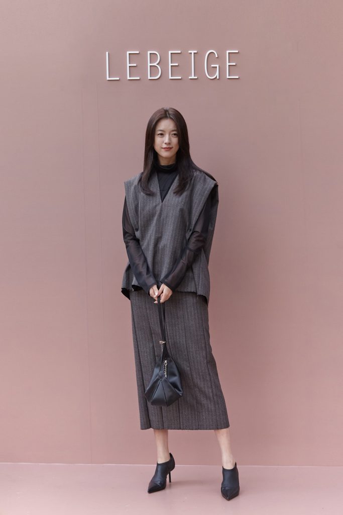 Actress Han Hyo-joo poses in front of the LEBEIGE logo backdrop at Gala de LEBEIGE, wearing a layered grey outfit with a black handbag.
