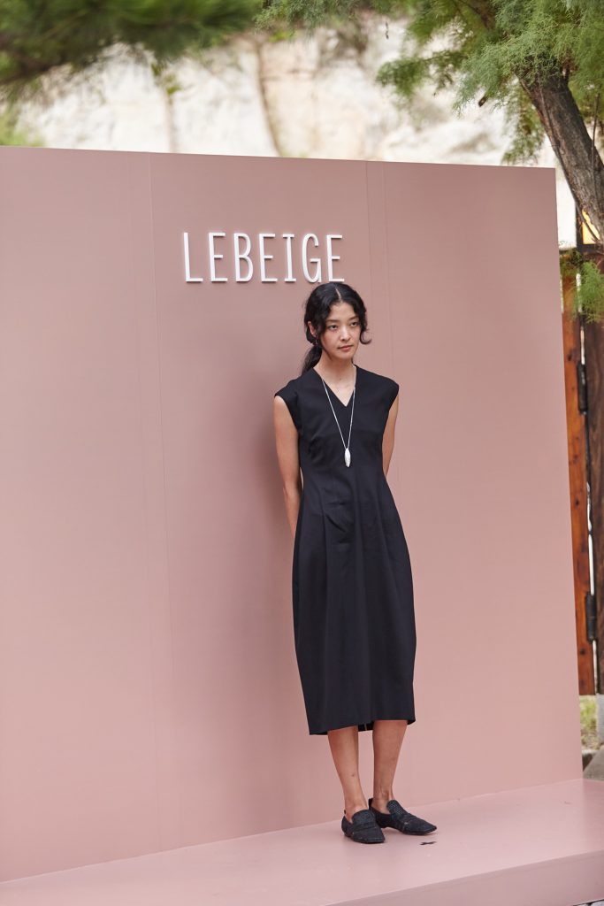 Model Kang So-young poses in front of the LEBEIGE logo backdrop at Gala de LEBEIGE, wearing a sleeveless black dress and long necklace.