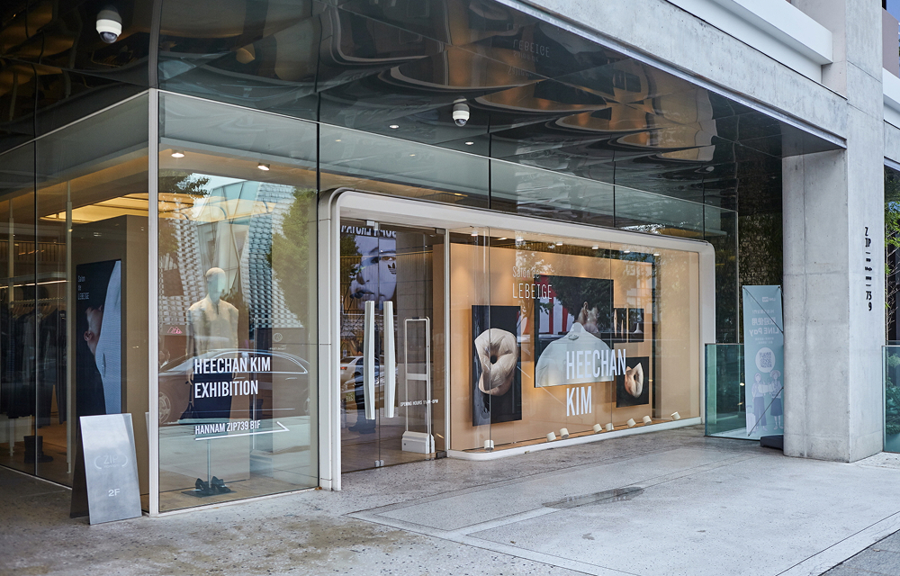 Glass storefront of ZIP739 Hannam displaying signage for the Salon de LEBEIGE exhibition with Heechan Kim, including artwork visuals and promotional posters.