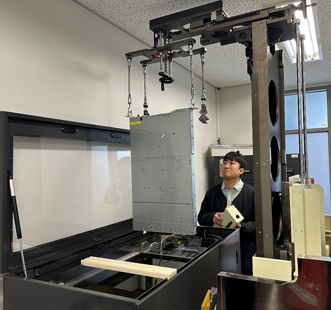 A Samsung C&T engineer lifts a server unit into immersion cooling equipment inside a test facility. 
