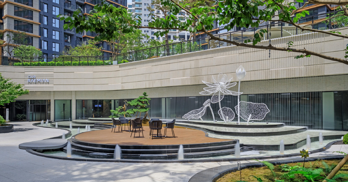 Courtyard at Raemian One Pentas with water features, seating area, and floral-inspired sculptures surrounded by greenery.