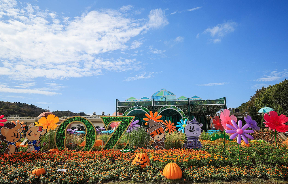 Colorful flower displays and “Oz”-themed characters decorate Everland’s Four Seasons Garden under a bright blue sky.