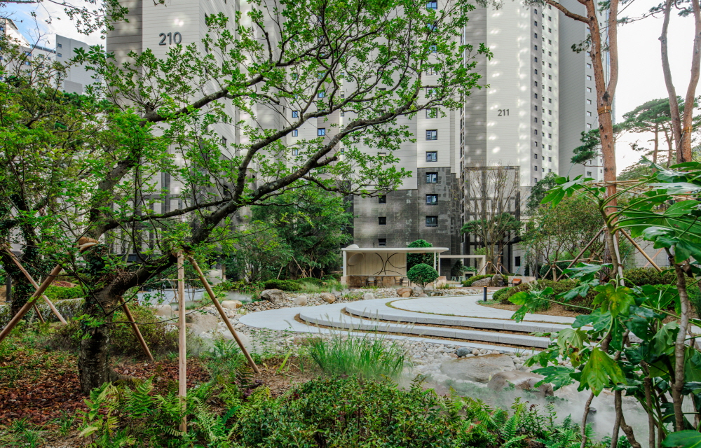 View of Raemian Forestige’s rain garden with stone pathways and lush greenery that fills with water after rain.
