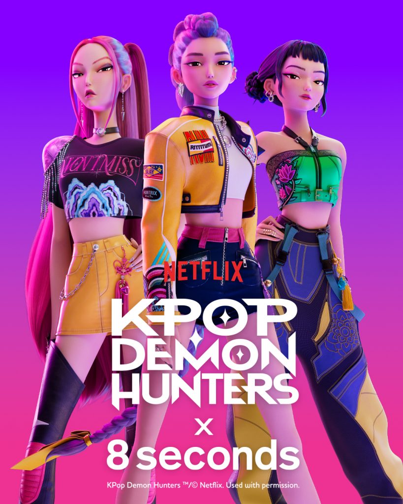 Promotional image showing three animated characters from K-Pop Demon Hunters representing the girl group “Huntrix.” They wear colorful performance outfits against a pink and purple gradient background with the logos of Netflix, K-Pop Demon Hunters, and 8seconds displayed below.