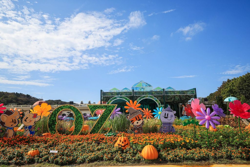 Decorative Oz-themed garden at Everland with colorful flowers, pumpkins, and cartoon characters under a clear blue sky.