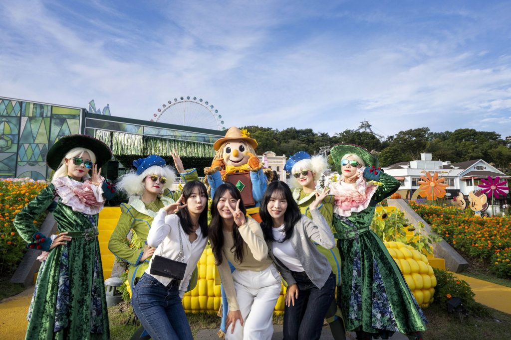 Group of visitors and costumed performers dressed as Oz characters smiling in front of Everland’s garden attractions.