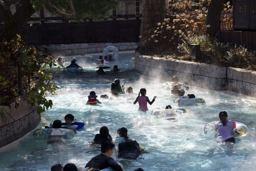 People drifting in tubes along the steaming Lazy River at Caribbean Bay amid fall trees.