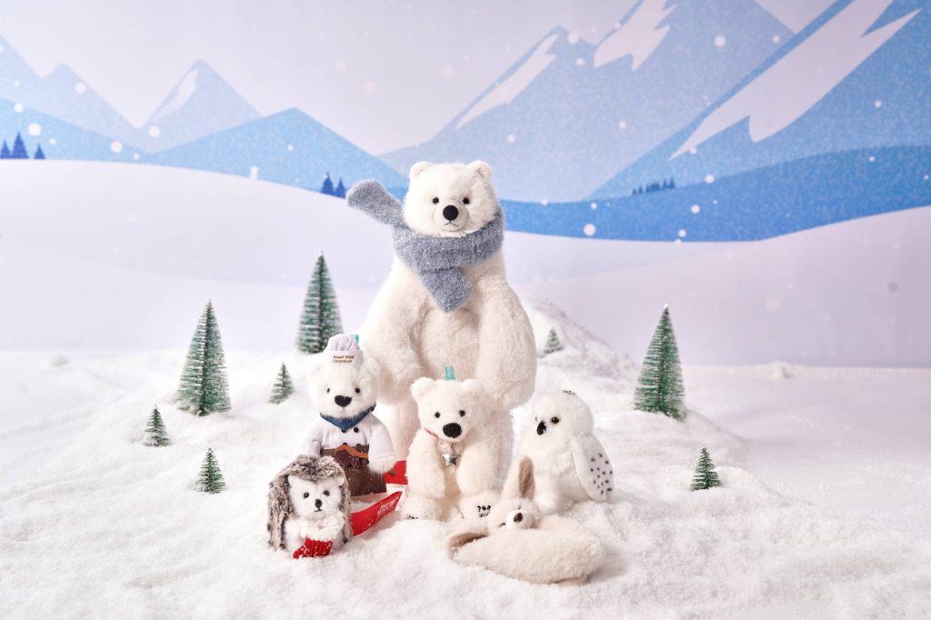 A group of winter-themed plush toys from Everland’s Bagel Wish Bear collection displayed in a snowy mountain scene, including a large polar bear with a blue scarf, a chef bear, a small polar bear keyring, a hedgehog, a white owl, and other winter animal plushies.