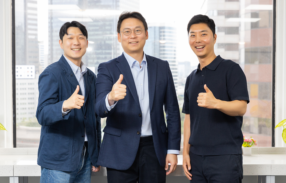 Three members of Samsung C&T’s Mining Materials Group photographed at the Seoul office with city buildings in the background