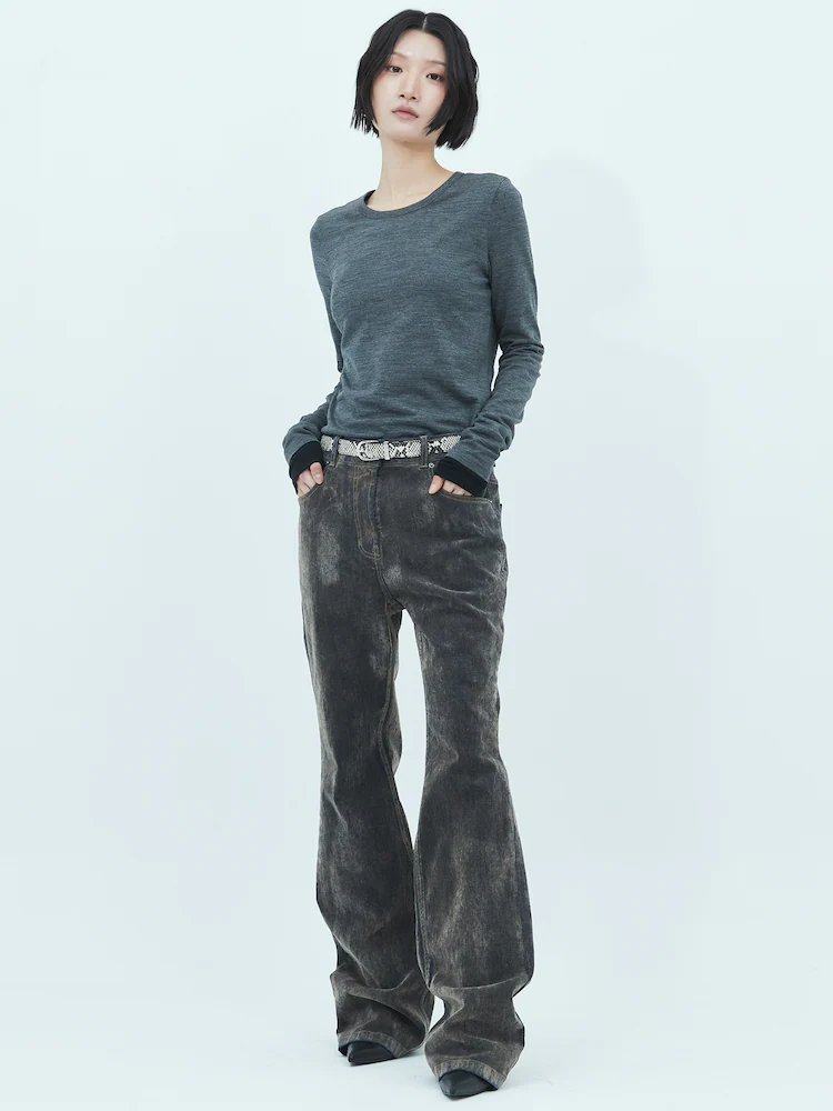 Model wearing beige velvet denim jeans paired with a fitted grey long-sleeve top, standing against a clean light blue studio backdrop.