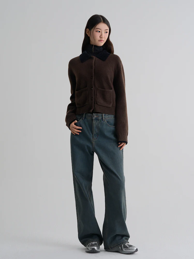 Model wearing a brown knit cardigan with a black velvet collar, styled with wide-leg denim against a light gray studio backdrop.