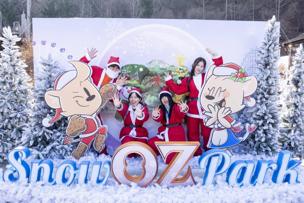 A group of visitors dressed as Santa take photos at Everland’s Snow OZ Park in Alpine Village, surrounded by winter-themed decorations.
