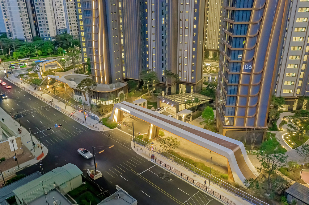 Evening view of Raemian One Pentas entrance gate and residential towers with warm architectural lighting along the façade and landscaped surroundings.