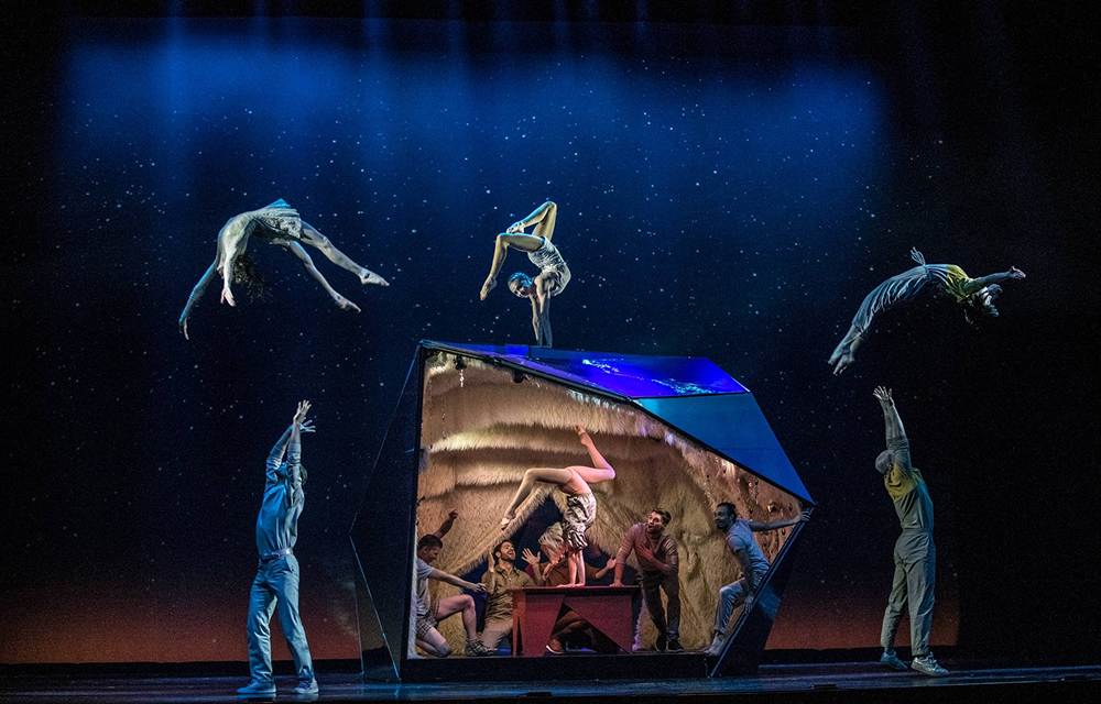 Acrobats perform on and around a geometric stage structure under blue lighting during a scene from Cirque Éloize’s Seul Ensemble in Montreal