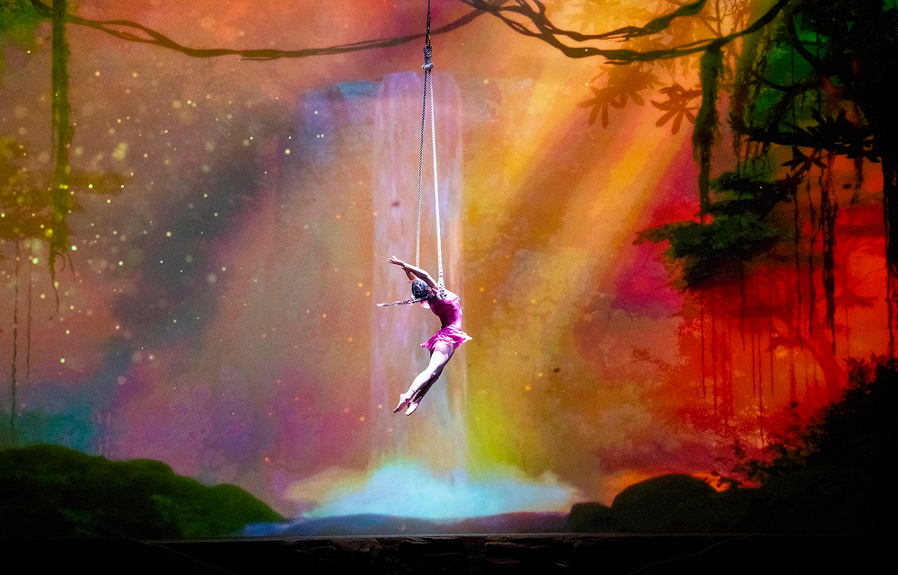 Cirque Éloize aerial performer suspended above stage with colorful backdrop during Wings of Memory at Everland.