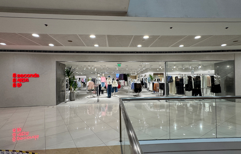 Wide exterior view of the newly opened 8seconds store at SM Megamall in Manila, featuring a minimalist storefront with red 8seconds signage and a bright interior showcasing clothing displays and mannequins