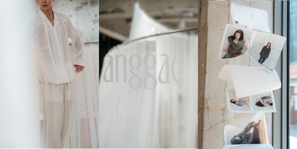 Model wearing a sheer white layered outfit from the 26SS collection by ‘anggae’, shown alongside white fabric displays and campaign images inside the Seongsu pop-up store.