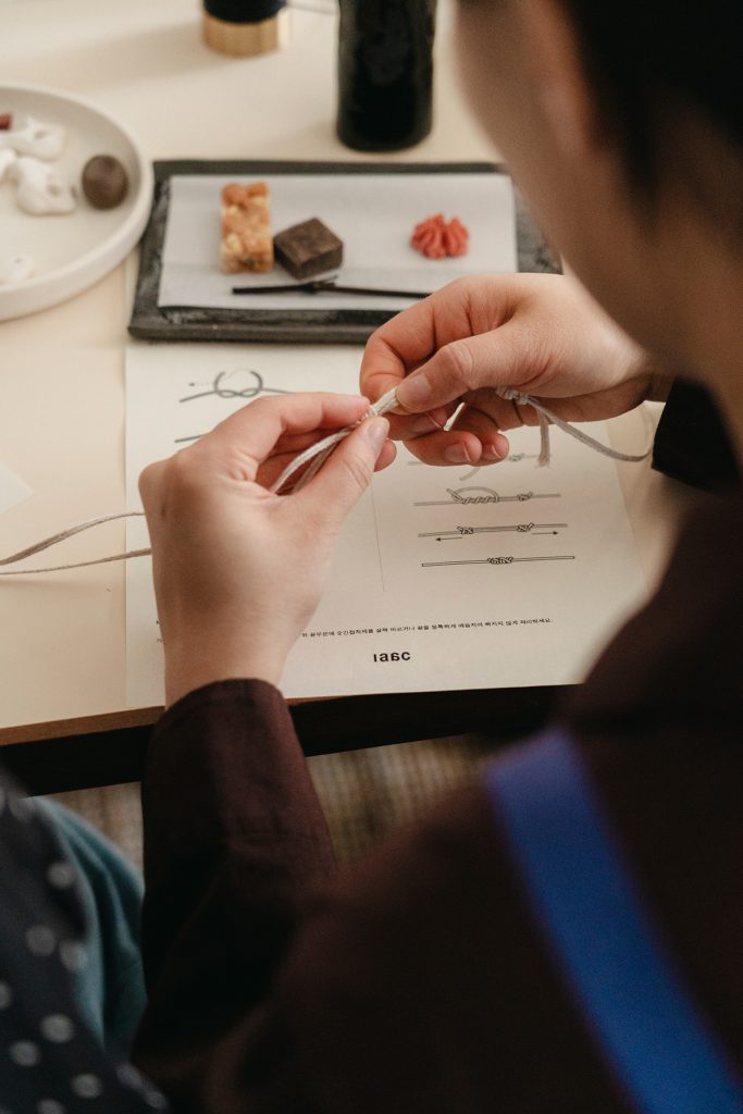 Visitor participating in a ceramic experience program at the 26SS pop-up store by ‘anggae’, creating a ceramic accessory at a table.