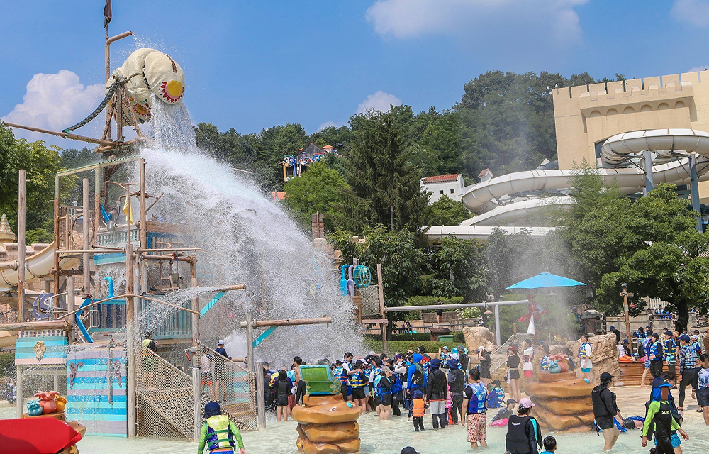 Visitors gather at Caribbean Bay’s Adventure Pool as a large water bucket pours water over the play area.