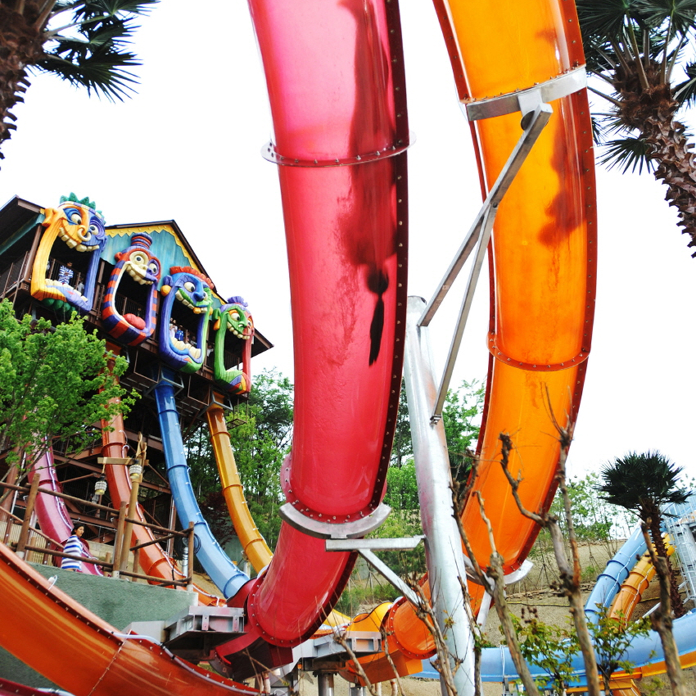Colorful red, orange, and blue Aqualoop water slide tubes curve through Caribbean Bay’s outdoor attraction area.