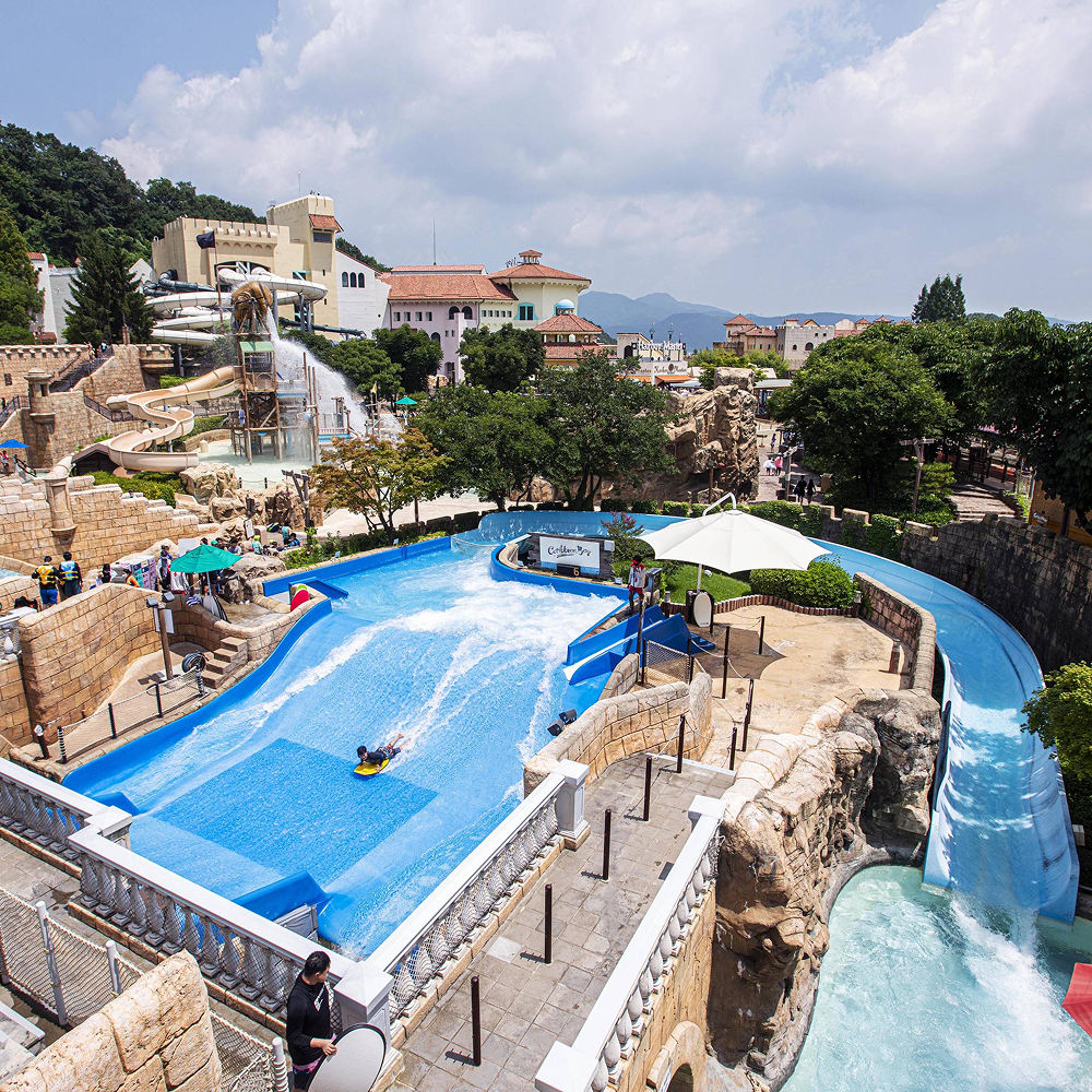 A visitor rides a board on Caribbean Bay’s Surfing Ride, with water slides and park buildings in the background.