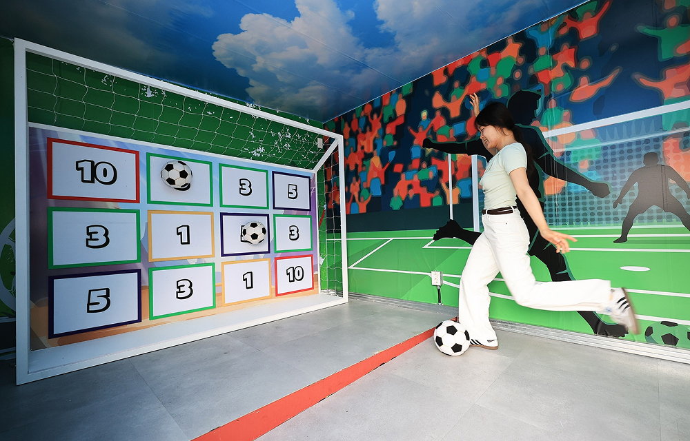 A visitor kicks a football toward a numbered bingo board inside a football-themed mission zone.