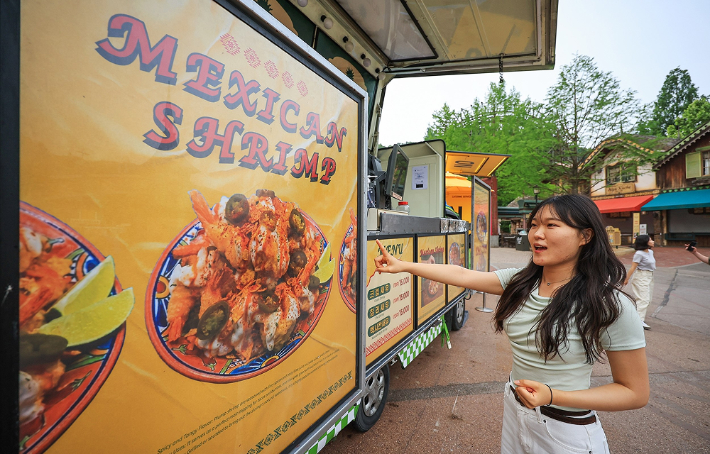 A visitor points at a Mexican shrimp menu displayed on a food truck at Everland’s Mexican Food Street.