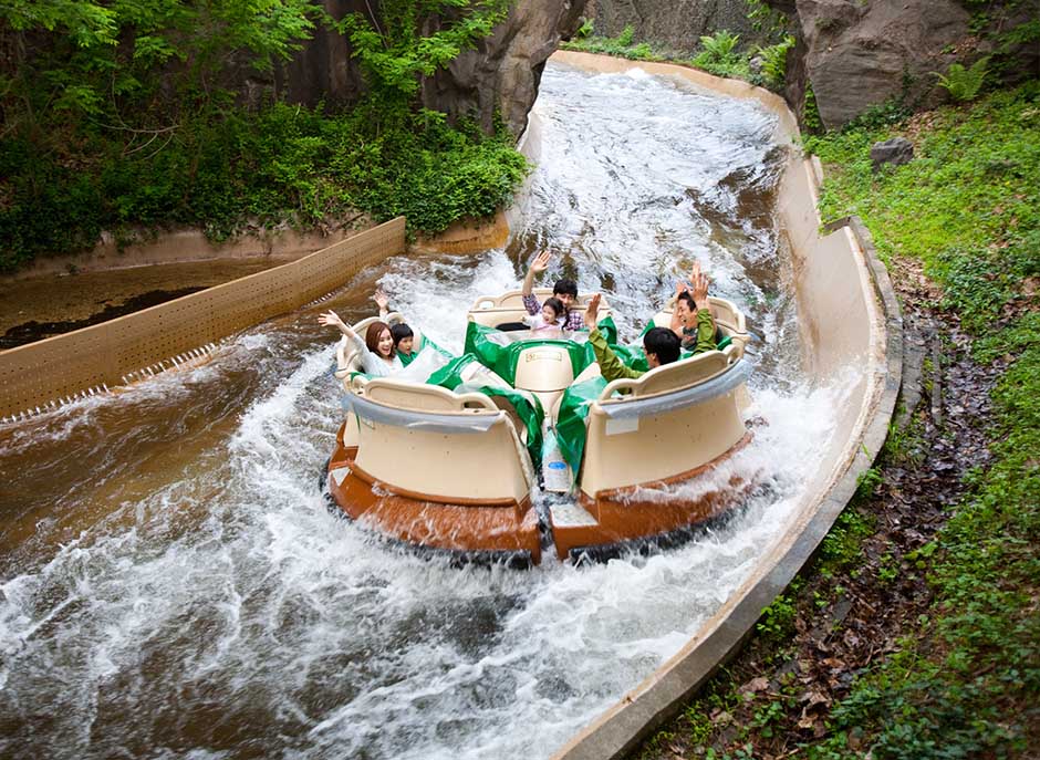 A circular raft carries visitors through a fast-moving water channel on Everland’s Amazon Express, surrounded by rocks and greenery.