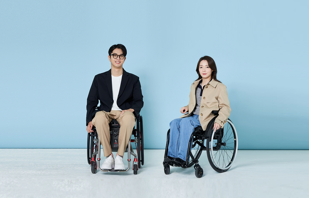 Two wheelchair users wearing Heartist business casual clothing against a light blue studio background.