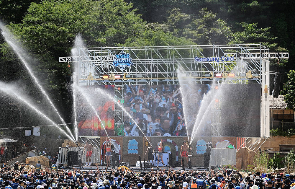 Visitors enjoy the Water Music Pool Party at Caribbean Bay’s outdoor wave pool, featuring live performances, water cannons, and a large LED stage