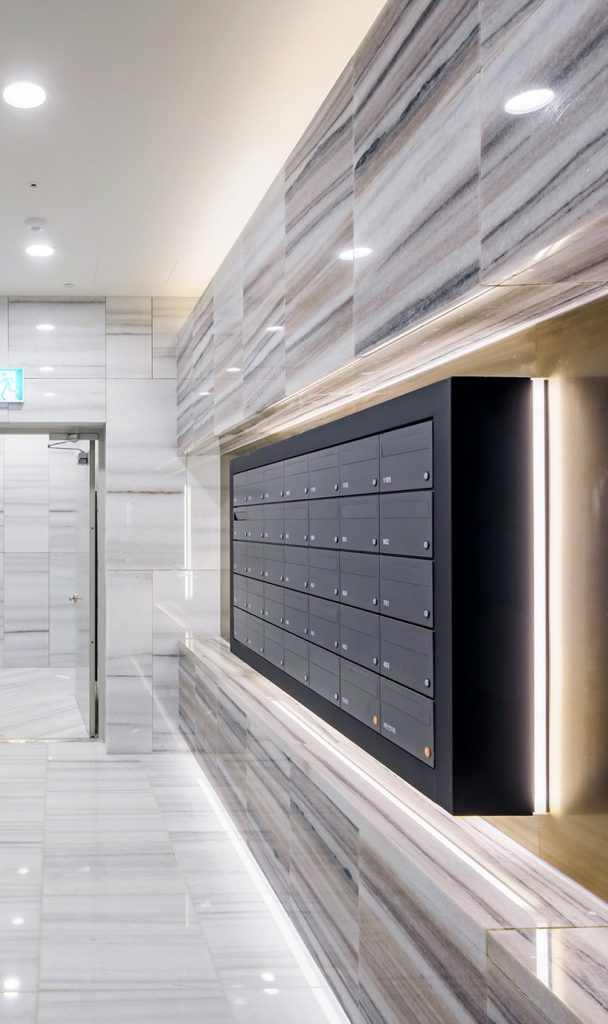 Raemian One Perla’s common lobby continues the arrival space design language with stone, metal details, and integrated lighting