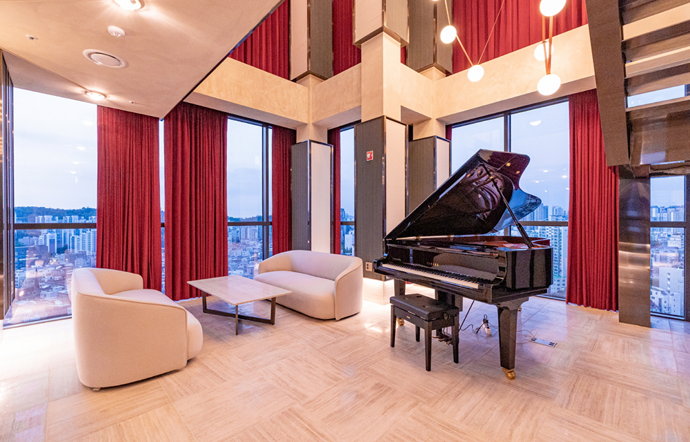 The sky lounge at Raemian One Perla offers a refined community space with panoramic views, warm interiors, and a grand piano centerpiece