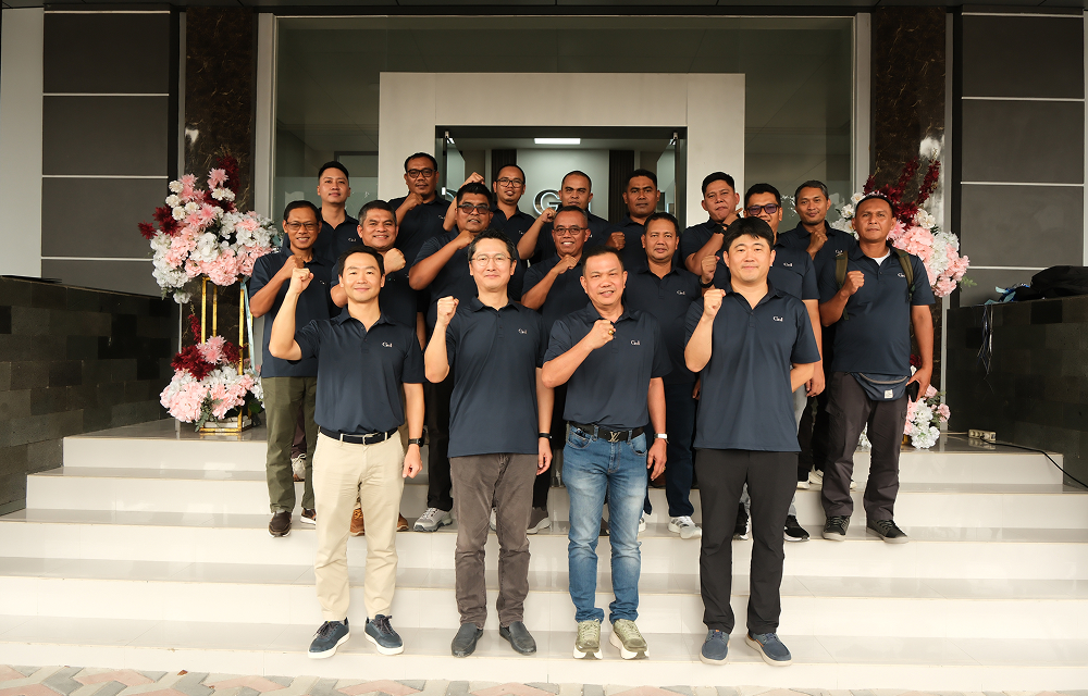 SNG employees pose together outside a building, raising their fists in a group photo.
