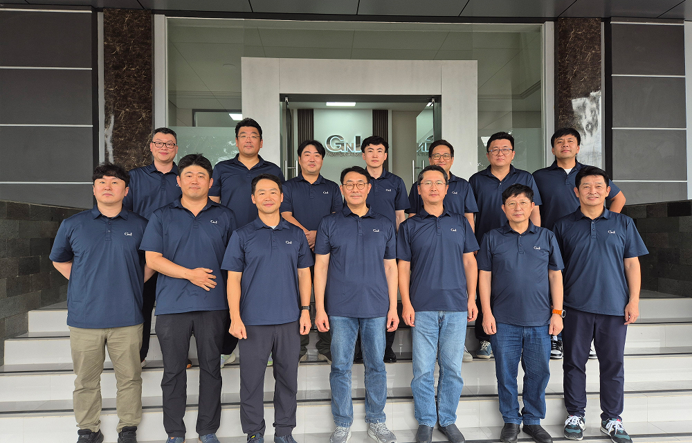 A group of SNG Korean employees pose together in front of an office building.