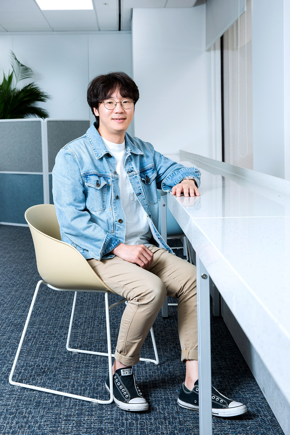 Junhyun Nam sits indoors near a table, facing the camera.
