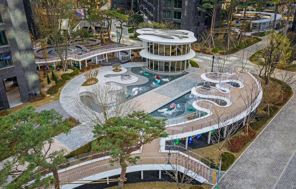 An aerial view highlights the garden’s flowing layout, including its central tea house, elevated deck, water features, seating areas, and winding walkways.