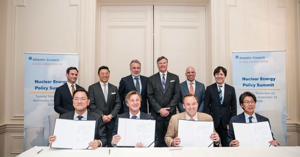 Four executives hold signed documents at the Atlantic Council Nuclear Energy Policy Summit in New York, with six representatives standing behind them. Seated from left are Jung Wook Kim of Samsung C&T, Rafał Kasprów of SGE, Scott Strazik of GE Vernova and Yasuhiro Takeuchi of Hitachi.